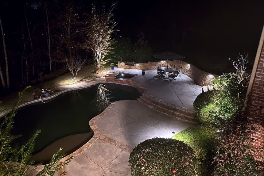 A pool and terrace lit at night
